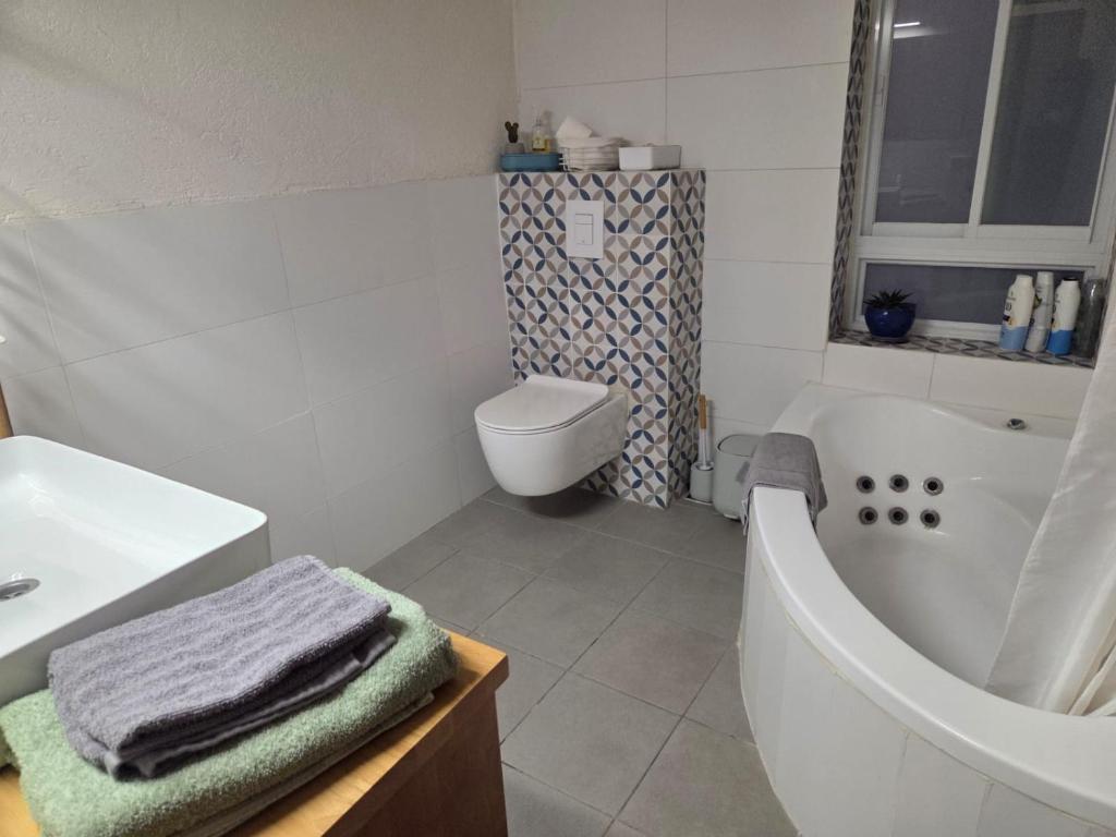 a bathroom with a tub and a toilet and a sink at הבית במושב in Umm el Shuf