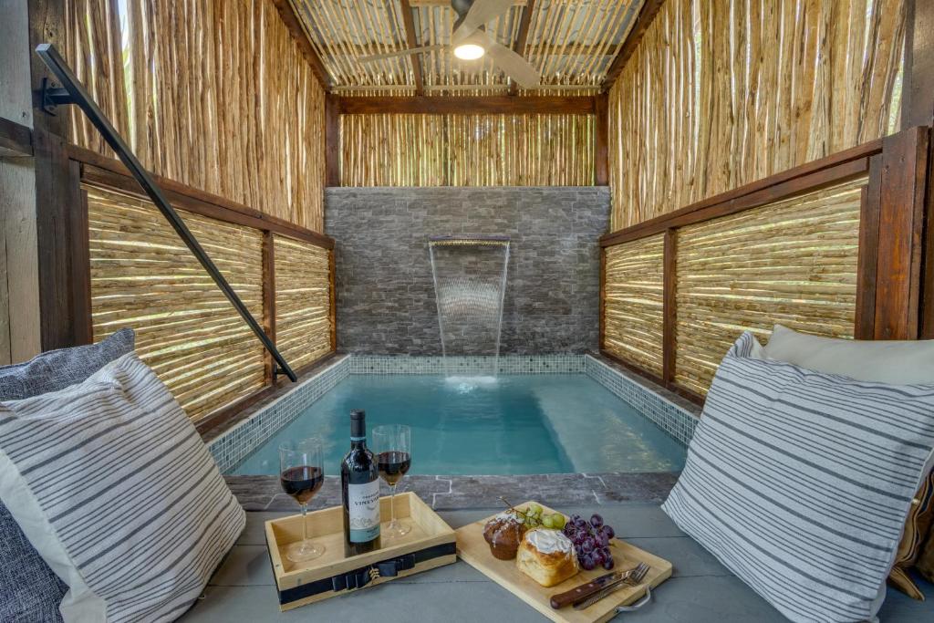 una bañera de hidromasaje con copas de vino y una bandeja de comida en Kmar Villas, en Placencia Village