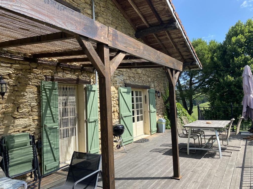 una terraza de madera con mesa y un edificio en Domaine du Cammazet, en Lapenne