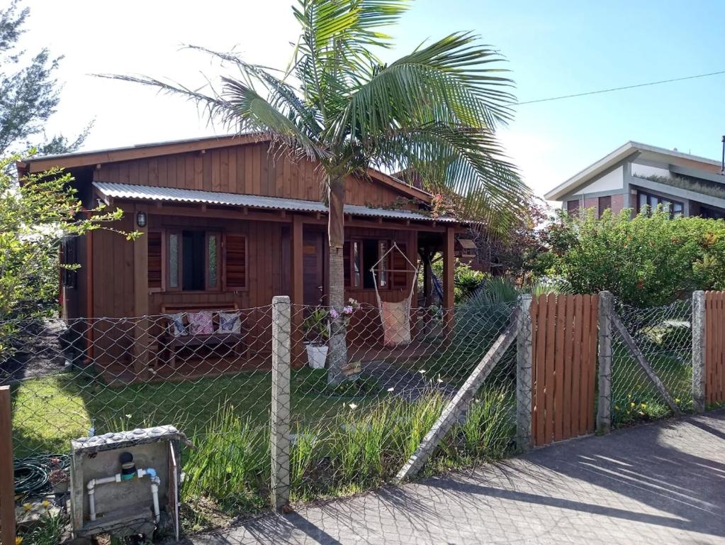 a house behind a fence with a palm tree at Recanto da Natureza in Imbituba