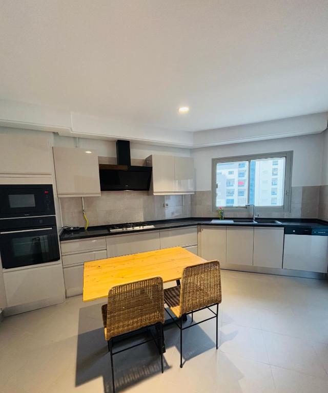 a kitchen with a wooden table and two chairs at Le somptueux du lac 2 in El Aouina Station