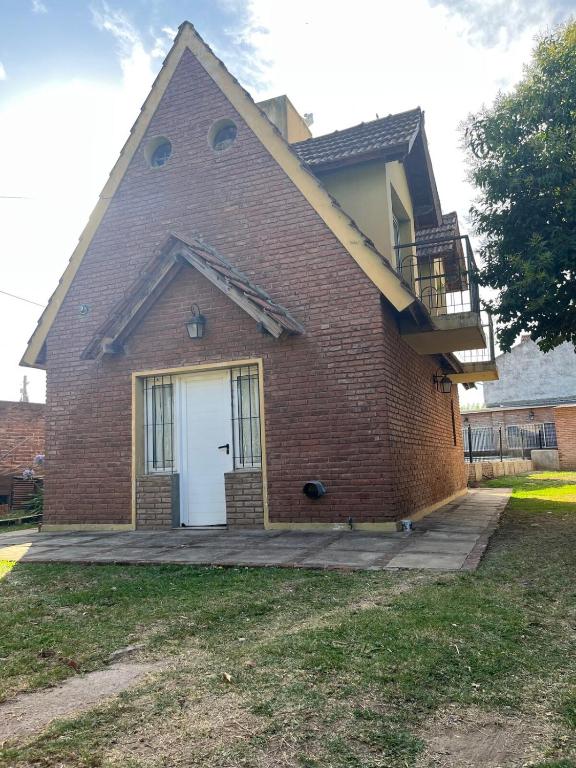 a brick house with a white door and a balcony at La Alpina in Chivilcoy
