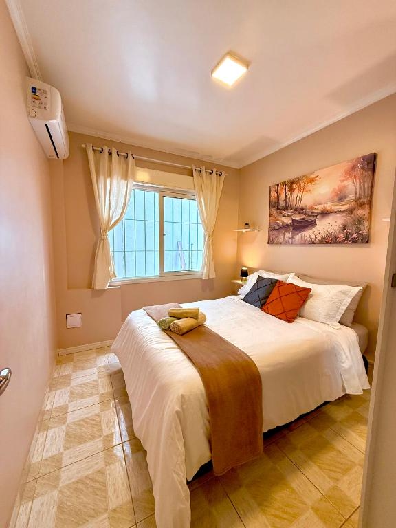 a bedroom with a large white bed and a window at Apto 2 dorm Centro de Capão 3 quadras do Mar box e churrasqueira in Capão da Canoa
