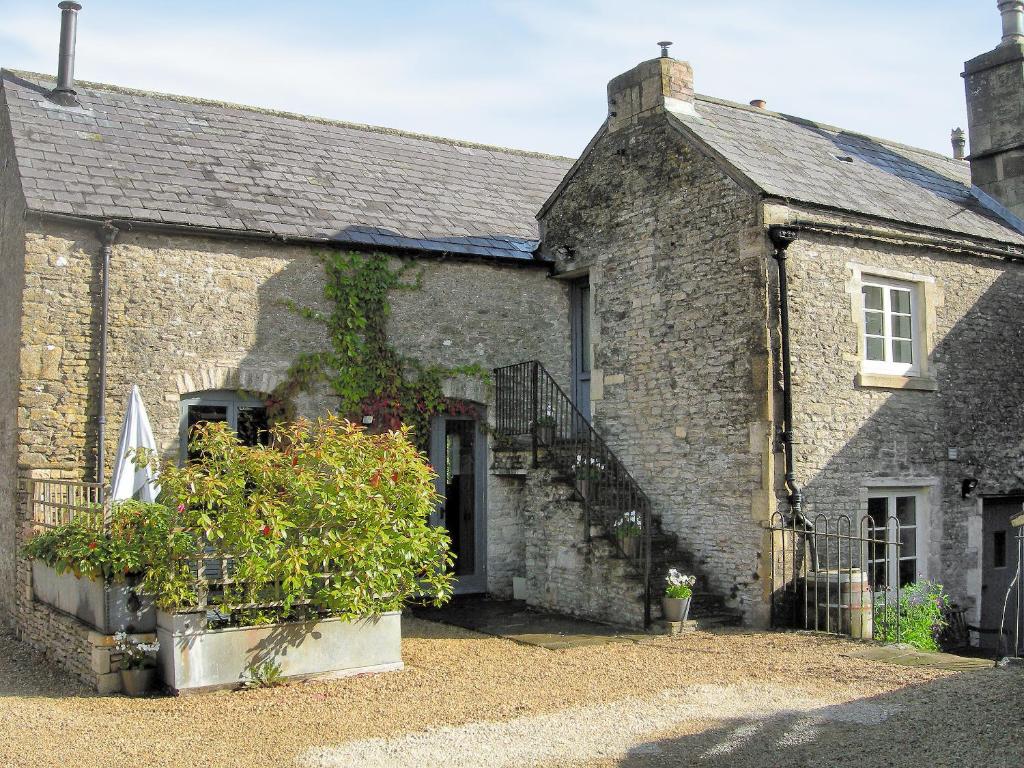 an old brick house with a staircase in front of it at Shaplands Barn in Cold Ashton