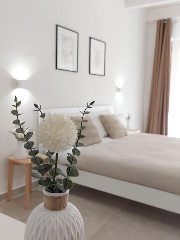 a white bedroom with a bed and a vase with a flower at DoMe Affittacamere in Iglesias