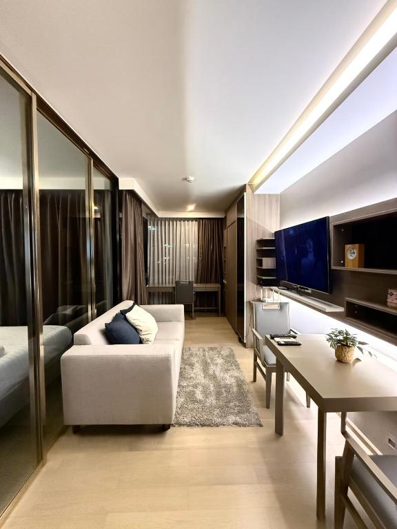 a living room with a white couch and a tv at Cozy room in Sukumvit in Bangkok