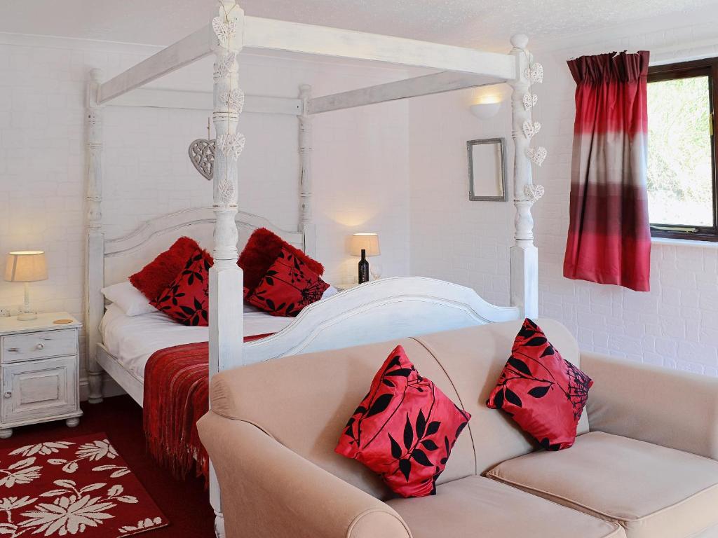 a bedroom with a four poster bed and a couch at River View Villa - Cv44 in Saint Cleer