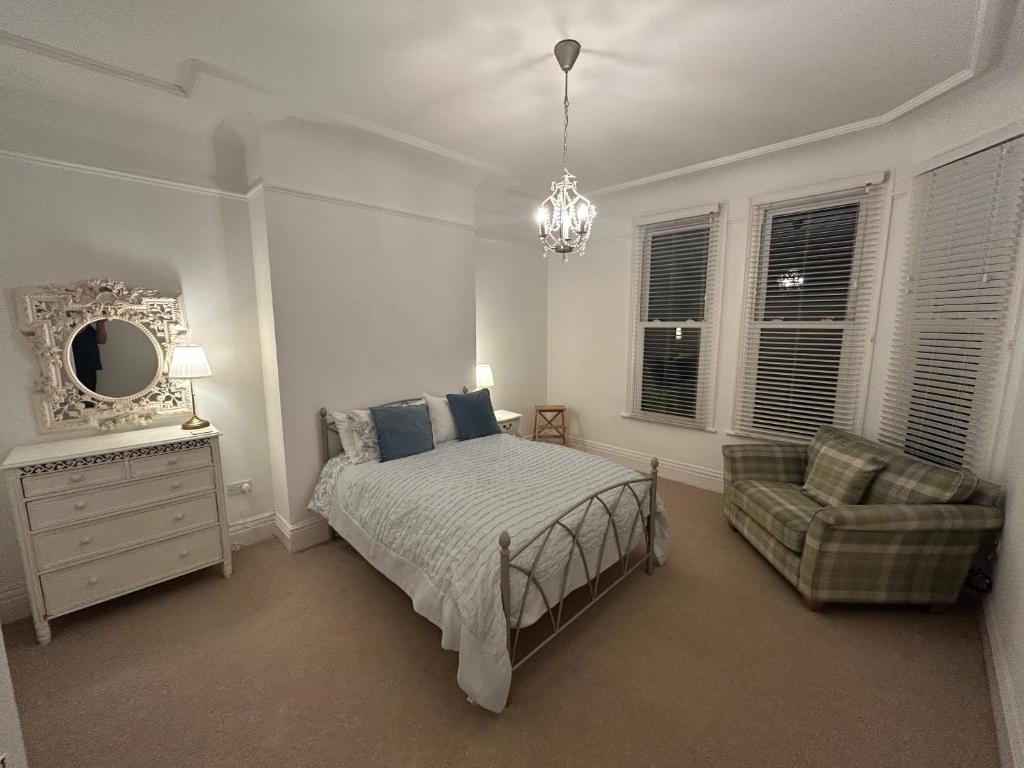a bedroom with a bed and a chair and a mirror at Banks Road in West Kirby