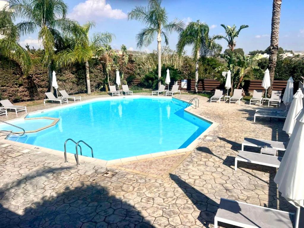 een zwembad met stoelen en palmbomen bij Seasons Retreat with pool and gym-2BR in Voroklini