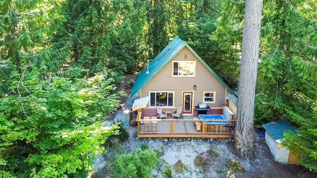 a small house with a deck in the woods at PNW River Cabin in Darrington