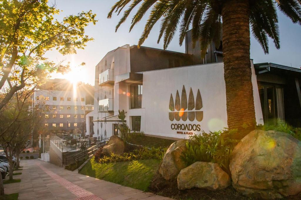 a building with a palm tree in front of a building at Coroados Hotel & Flats in Nova Prata