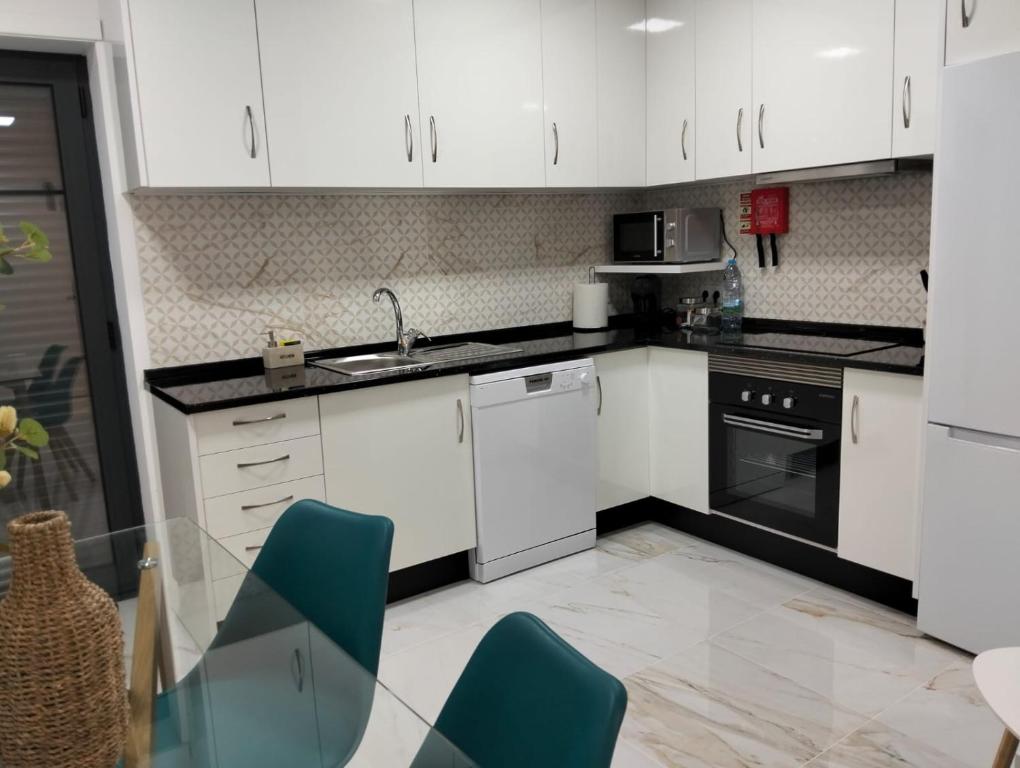 a kitchen with white cabinets and a table and chairs at Costa Home in Gafanha da Nazaré