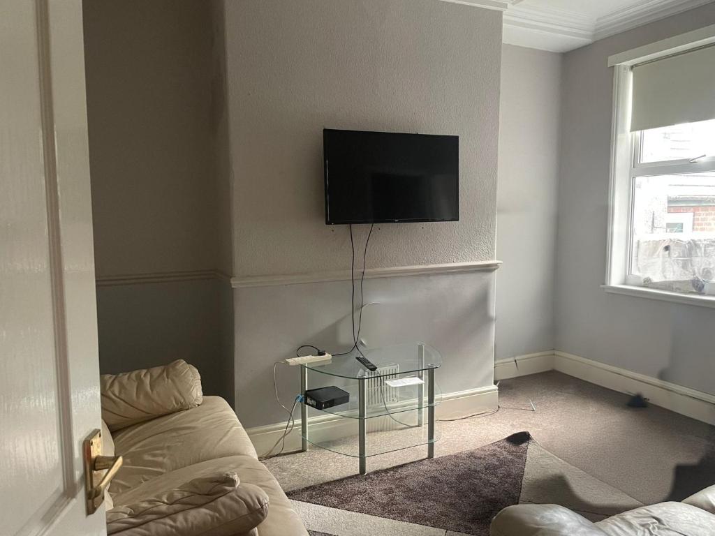 a living room with a couch and a tv on the wall at Modern Double Rooms Near Stoke City Centre and Staffordshire Uni in Stoke on Trent