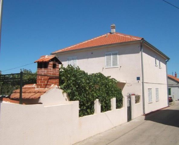 ein weißes Haus mit einem Zaun davor in der Unterkunft Apartments Emil in Murter