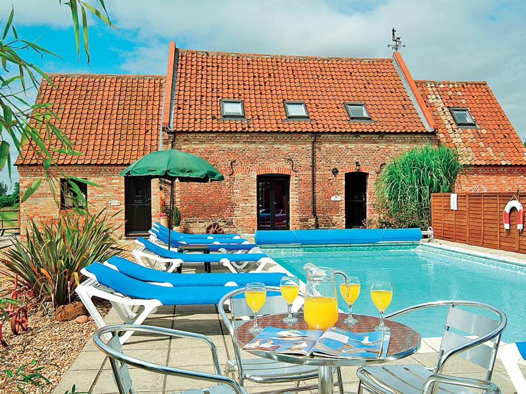 a patio with a table and chairs and a swimming pool at Rafters Barn - E2064A in Runcton Holme