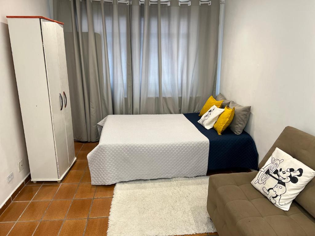Un dormitorio pequeño con una cama y un sofá. en Praia Grande Aviação Apto Disney, en Praia Grande