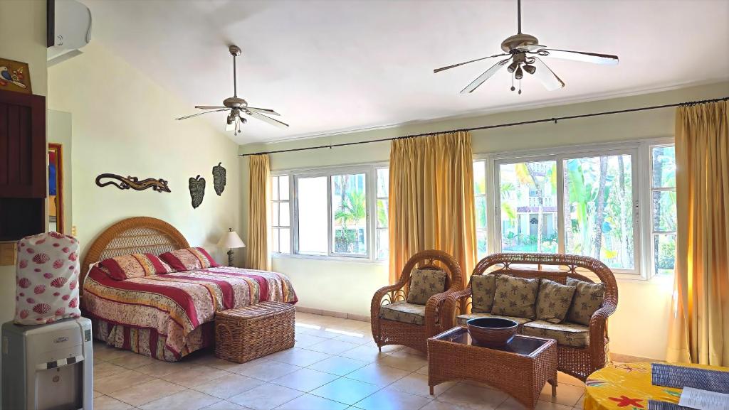 a bedroom with a bed and chairs and windows at Ocean Dream 1st See Line Studio in Cabarete