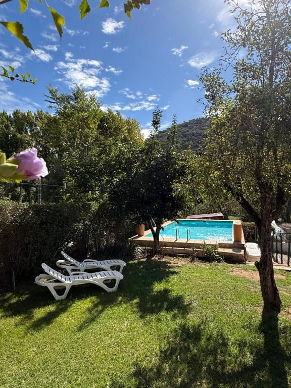 zwei weiße Stühle im Gras neben einem Pool in der Unterkunft Casa Rural Orilla del Hueznar in Cazalla de la Sierra