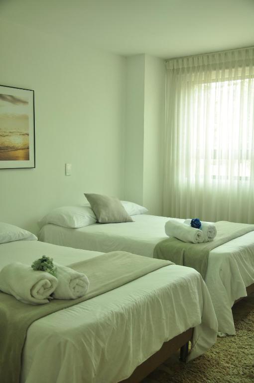 a bedroom with three beds with towels on them at live Medellín desde un Apartamento Céntrico y Cómodo in Medellín