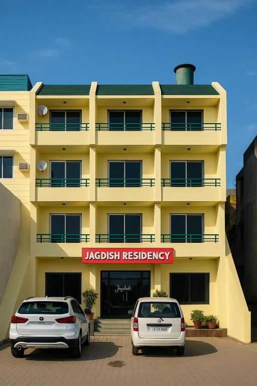 two cars parked in front of a yellow building at HOTEL Grand JAGDISH RESIDENCY in Katra
