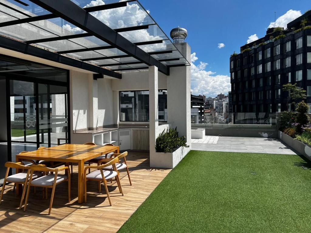 d'une terrasse sur le toit avec une table et des chaises en bois. dans l'établissement Departamento la Carolina - Centro financiero y comercial Quito, à Quito