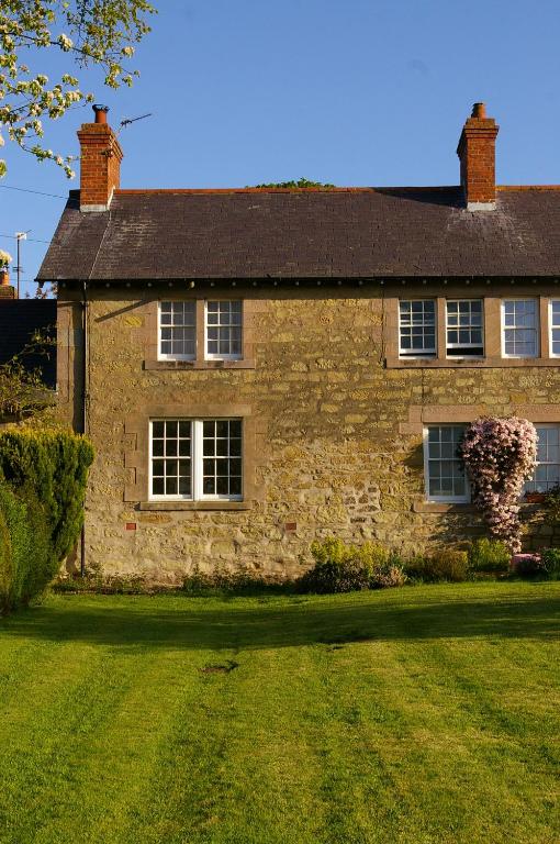 a stone house with a grass yard in front of it at The Cottage in Etal
