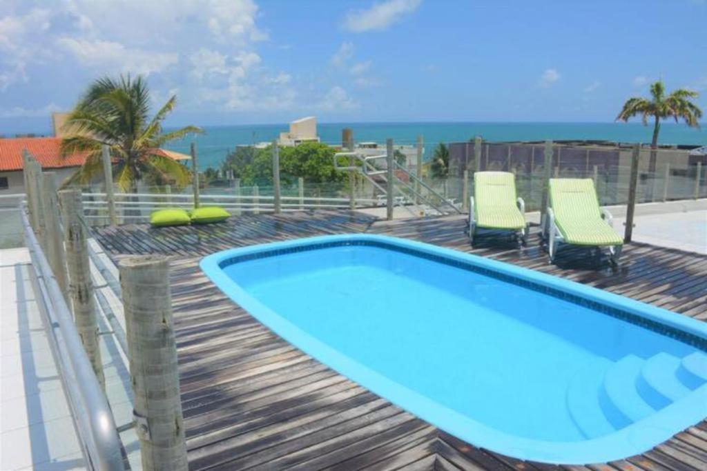 a swimming pool on a deck with chairs and the ocean at Joan Miro Flat - Ponta Negra in Natal