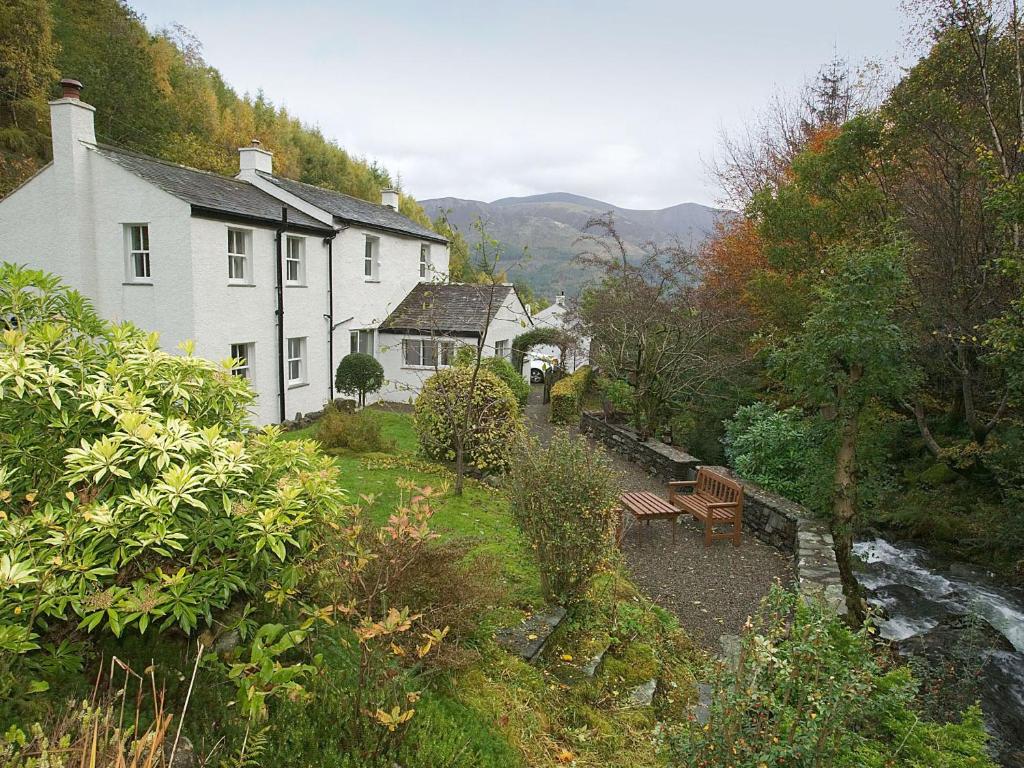 a white house with a river in front of it at Joan's Cottage in Braithwaite