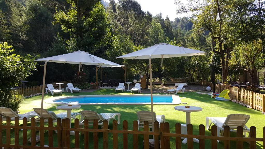 a backyard with a pool with chairs and umbrellas at Cal Mosqueta in Sant Llorenç de Morunys