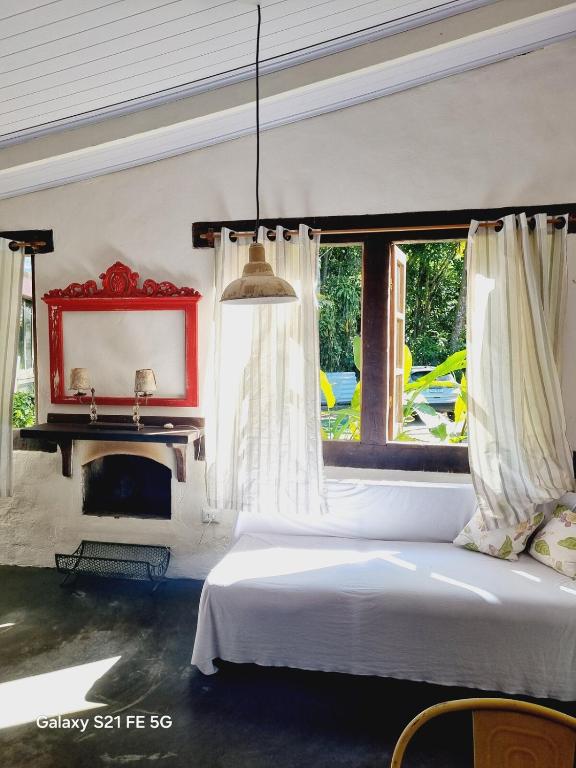 ein Schlafzimmer mit einem weißen Bett und einem Kamin in der Unterkunft Cabana CasaBah in São Sebastião