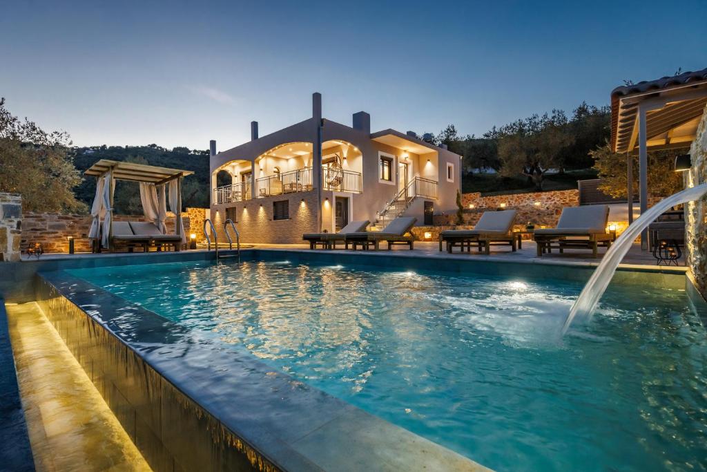 a swimming pool with a fountain in front of a house at Luxury VILLA RAFAEL in Skopelos Town