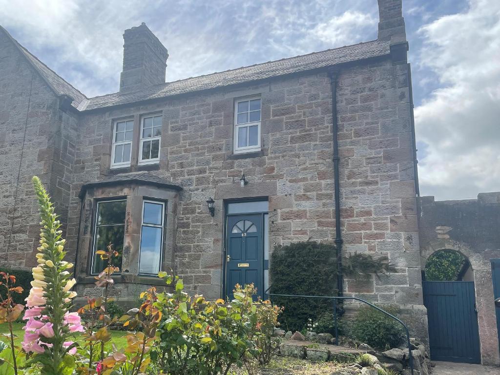een oud bakstenen huis met een blauwe deur bij Tarn House in Wooler