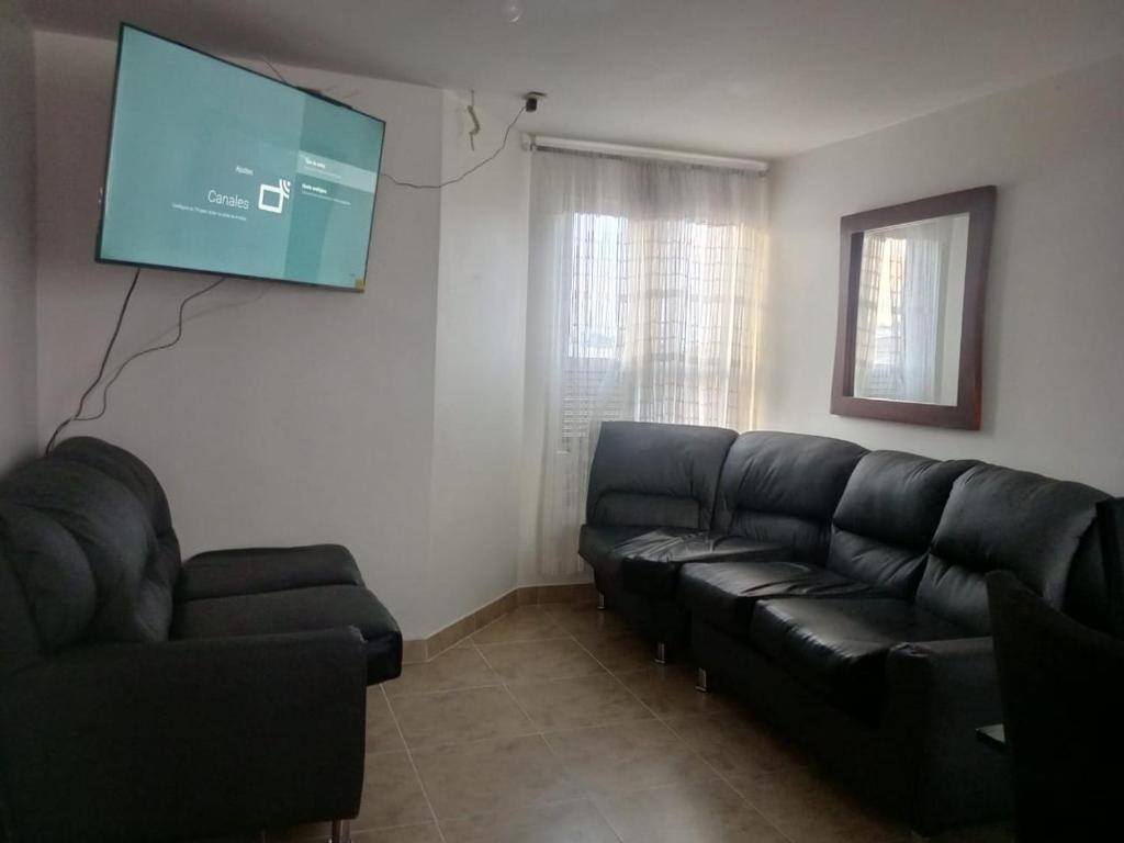 een woonkamer met een zwarte bank en een flatscreen-tv bij Apartment in Bogotá in Bogota