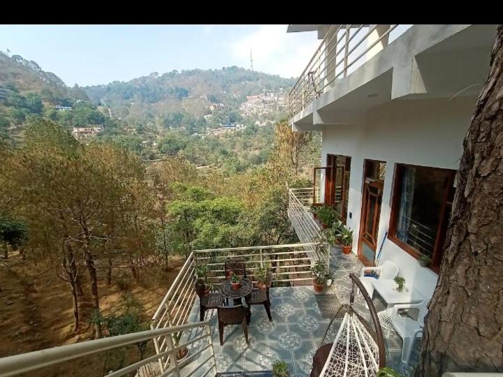 a balcony of a house with a table and chairs at Fourseasonkasauli in Solan