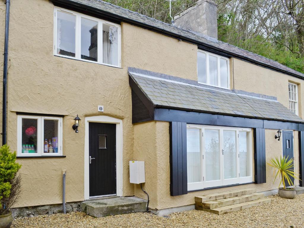 a yellow house with a black door and windows at Stable Cottage in Penrhyn Bay