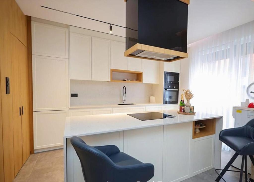 a kitchen with white cabinets and a sink and chairs at Apartament Modern in Kosovo Polje