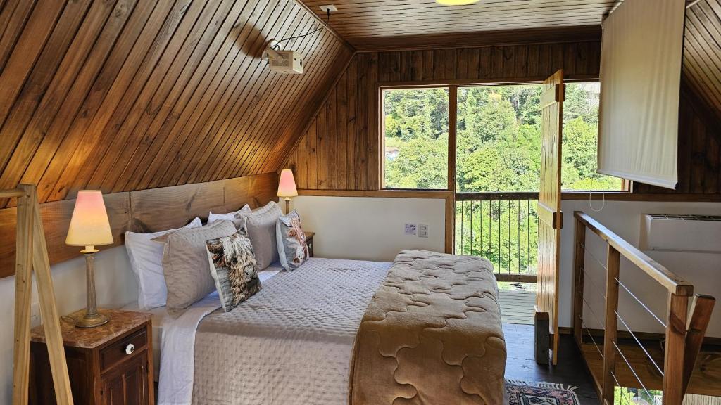 a bedroom with a bed in a room with a window at Le Ville - Chalé 1 in Campos do Jordão