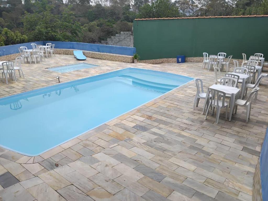 a swimming pool with chairs and a table and a table and chairsitures at Chácara Amorim in Mairiporã