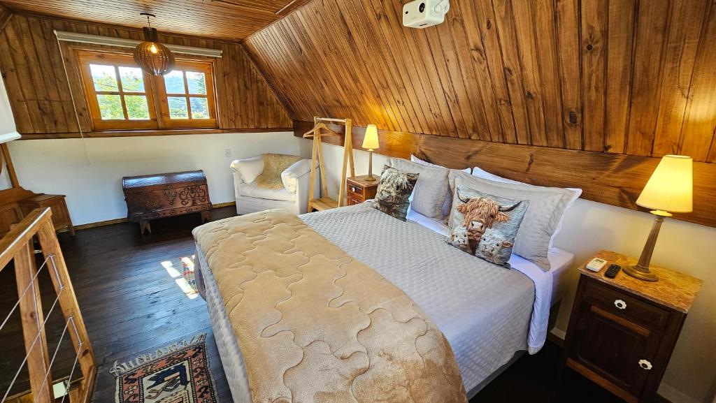 een slaapkamer met een groot bed in een kamer met houten wanden bij Le Ville - Chalé 1 in Campos do Jordão