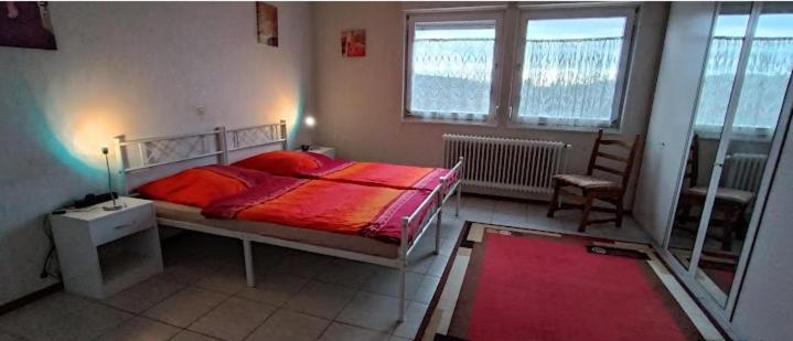 una camera da letto con un letto con lenzuola rosse e una finestra di Albferienhaus Schaette a Giengen an der Brenz