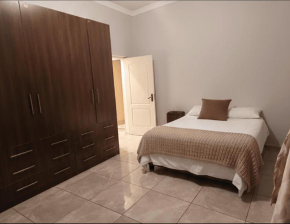 a bedroom with a bed and a large wooden cabinet at The Mining Station in Randfontein