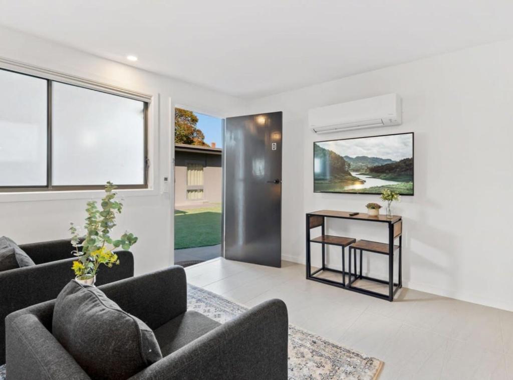 a living room with two couches and a table at Cozy 1-Bed Studio Near Cafes and Shops in Carnegie