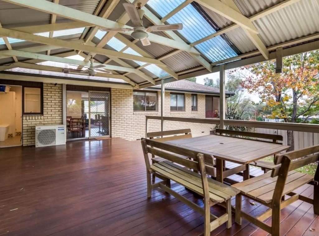 a patio with a wooden table and benches on a deck at Spacious and Restful Holiday Home with Backyard in Weetangerra