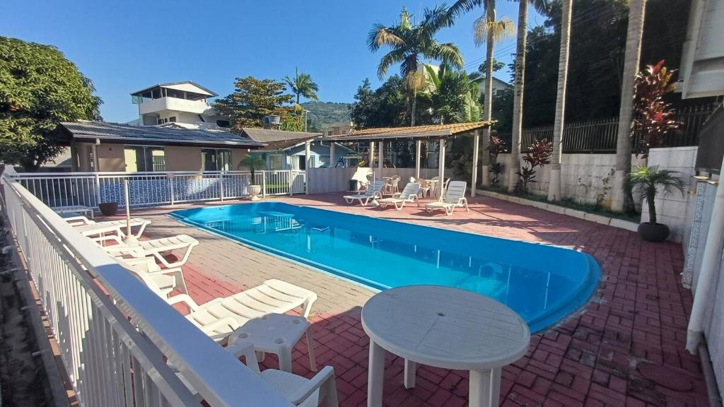 a swimming pool with white chairs and a table next to it at Res Diego Marcelo DS2 - Casa Completa 2 Dorm, Piscina, AR, WIFI, Churrasqueira in Itapema