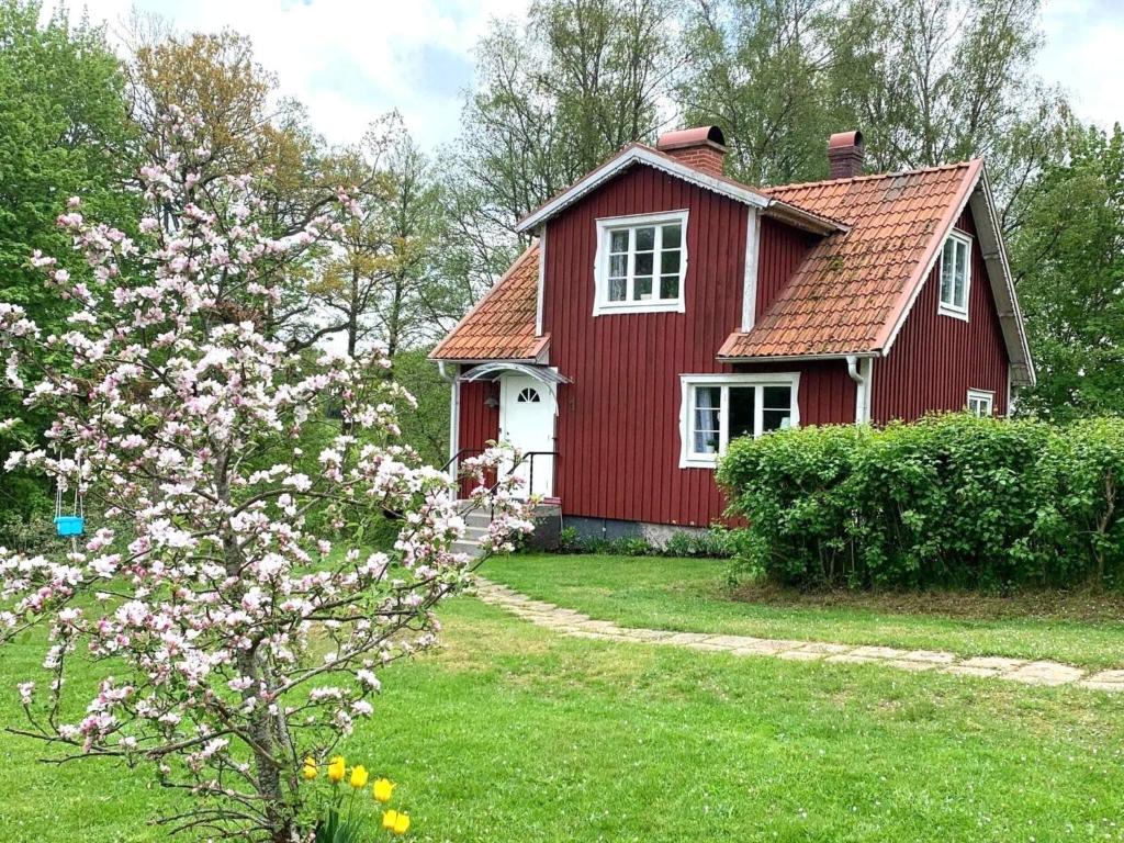 a red house with a flowering tree in front of it at 5 person holiday home in Tving in Tving