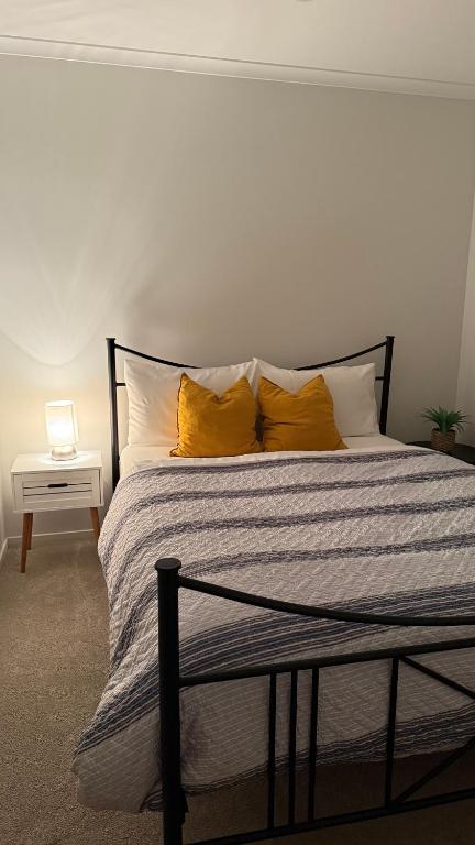 a bedroom with a bed with yellow pillows at Stay with the Singhs in Rolleston