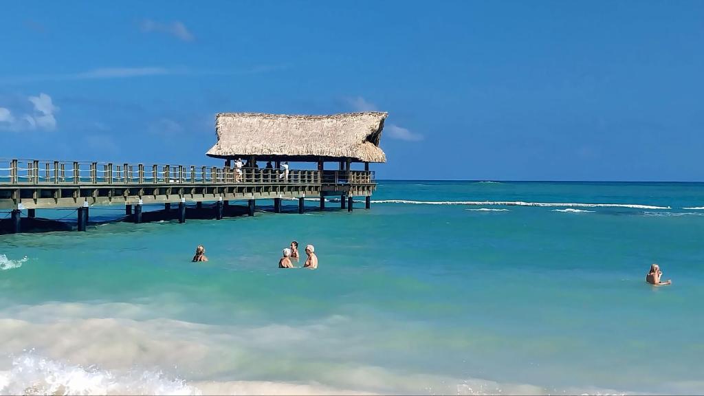 a group of people in the water near a pier at Punta Cana Aruba Beach Apartcomplex 1 in Punta Cana