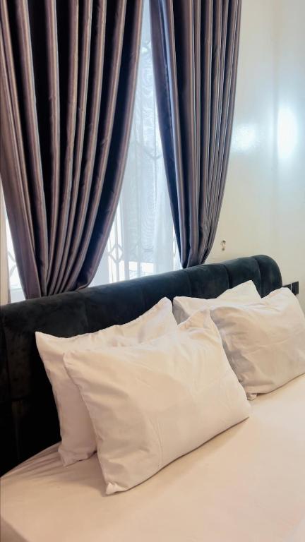 a bed with white pillows in front of a window at Short Stay LTD in Lekki