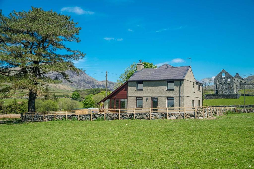 a large house in a field with a tree at Bryn-Weirglodd in Llanfihangel-y-pennant