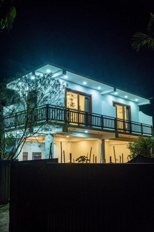 a house lit up at night with a balcony at Bailey Beach Villa in Ahangama